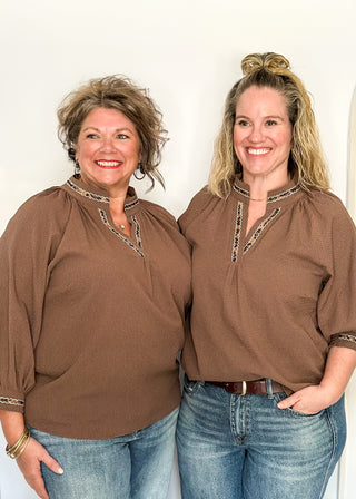 Chocolate brown v-neck top with 3/4 length sleeve, leopard lace detail around sleeve, collar, and v-neck.