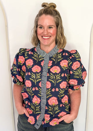 Navy floral puff sleeve blouse with pink oversized floral print and striped contrast trim along the neckline and front placket.
