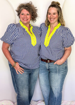 Women’s gingham blouse with decorative buttons and statement neckline detail.