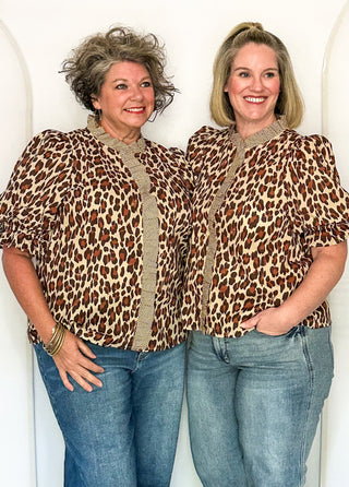 Two women wearing a short sleeve leopard print top with ruffle front.