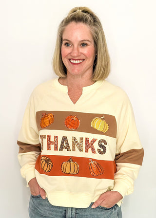 woman modeling a cream long sleeve top with pumpkins and THANKS in sequins