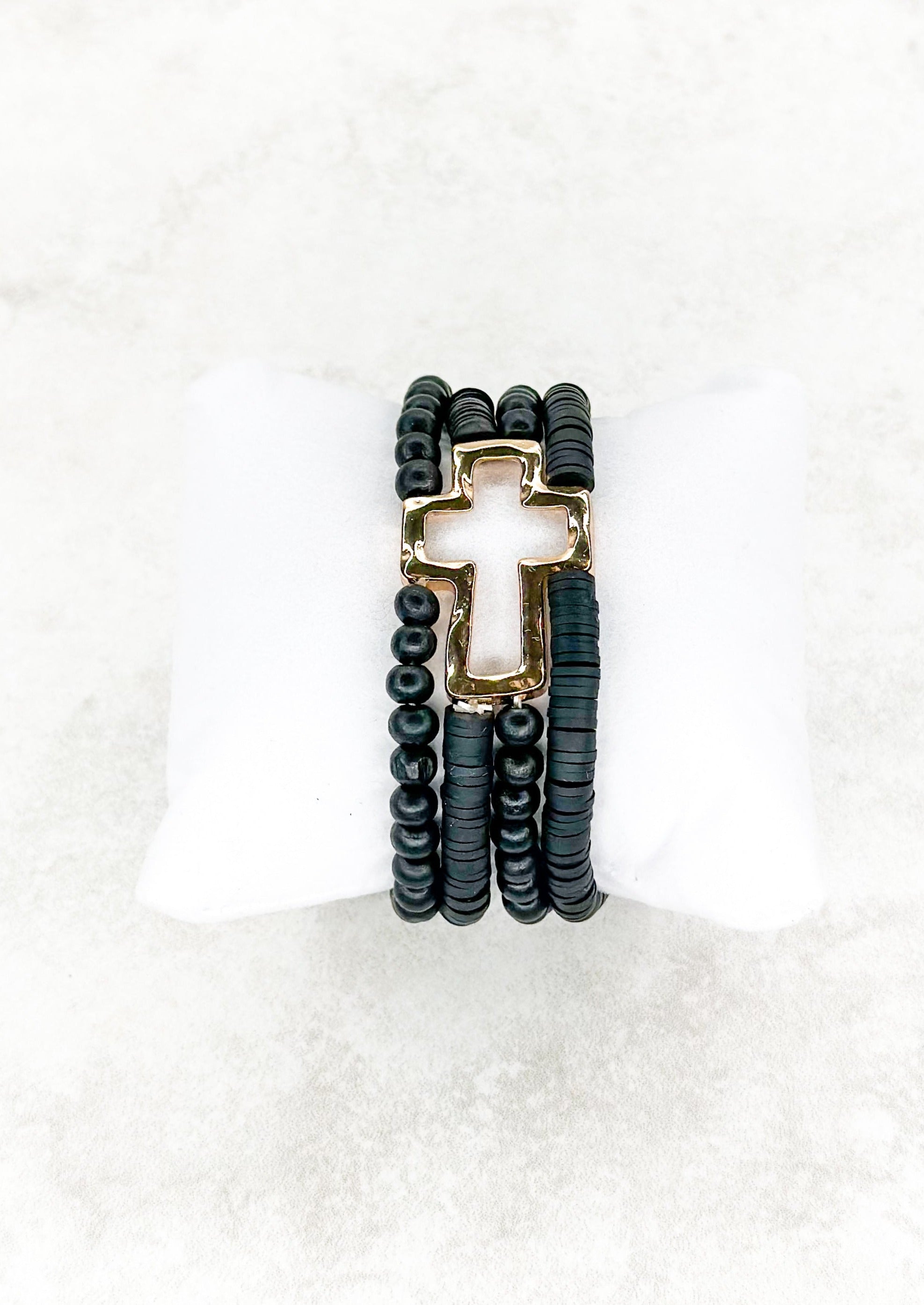 Four strand black beaded stretch bracelet attached to open gold cross.
