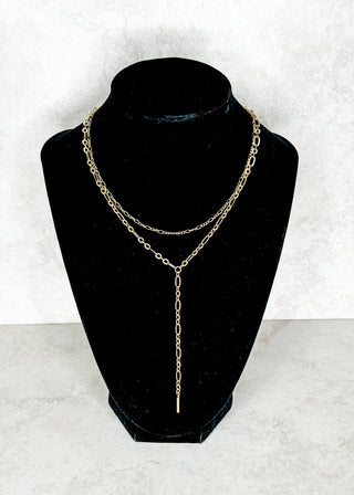 Gold chain necklace on a black mannequin bust against a white background