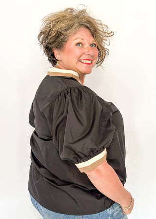 Person wearing a black blouse with puffed sleeves against a white background