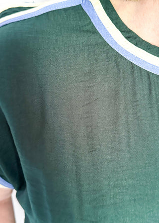 Close-up of a person wearing a dark green short-sleeve top with a striped crew neck in white and light blue.