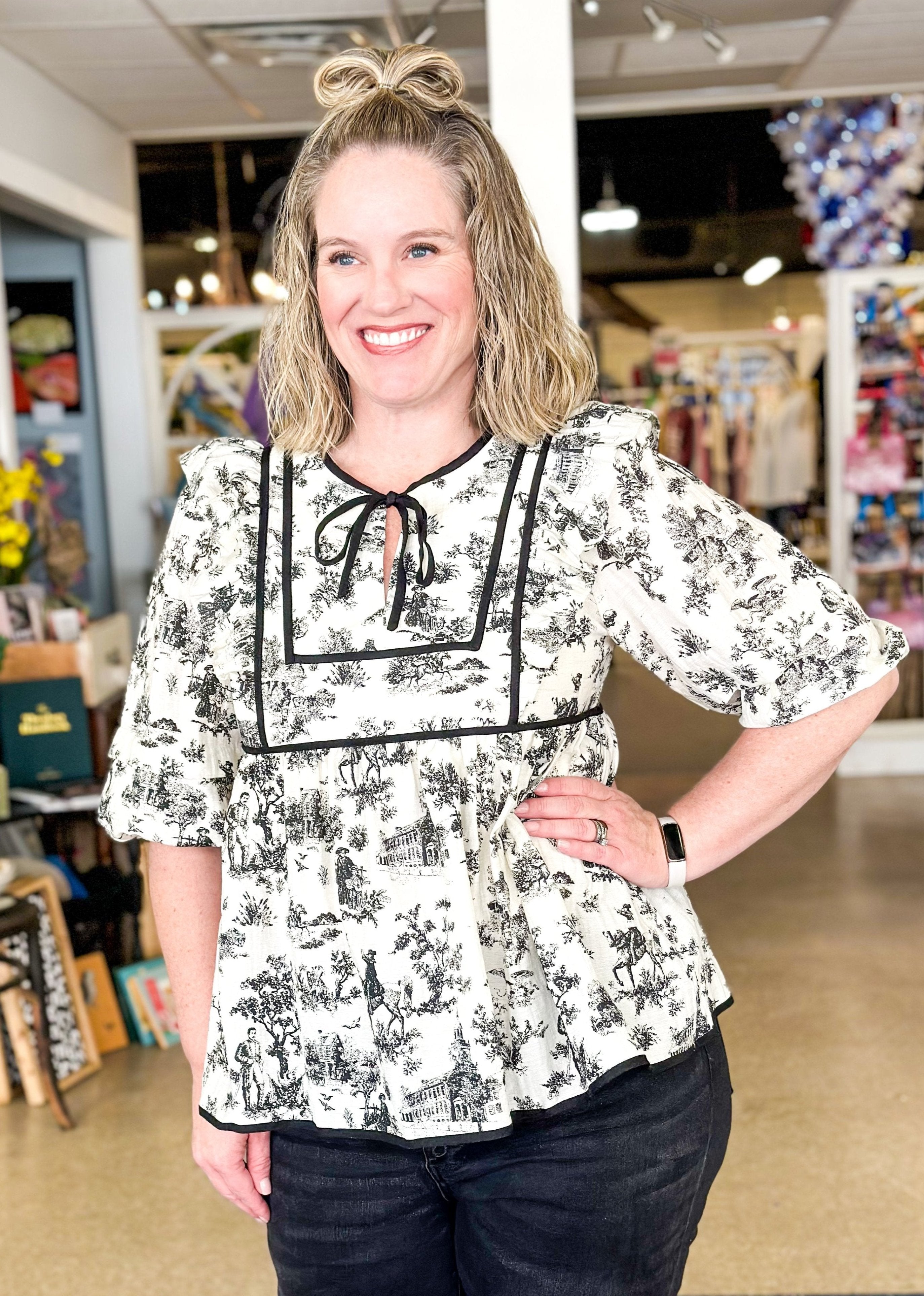 babydoll top with black floral print and black piping detail and tie neck - elastic around cuff of sleeve that hits right above the elbow