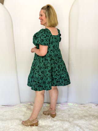 side view of woman wearing Forest green jacquard babydoll dress with square neckline and short sleeves.