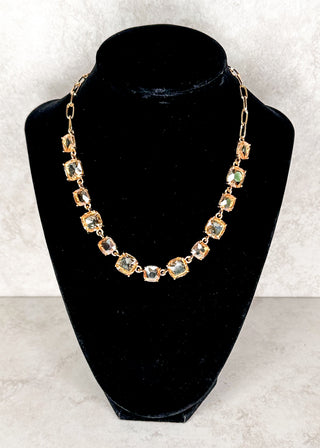 Gemstone necklace in champagne and gold displayed on a black neck form