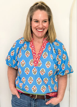 Bright blue 3/4 sleeve top with floral pattern, smocked collar with matching coral floral neckline and hem. 