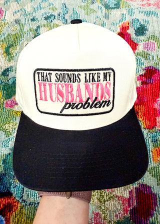 Snap-back canvas hat with black bill.  Embroidered patch with "That Sounds Like My Husbands Problem" in Hot pink and black. 