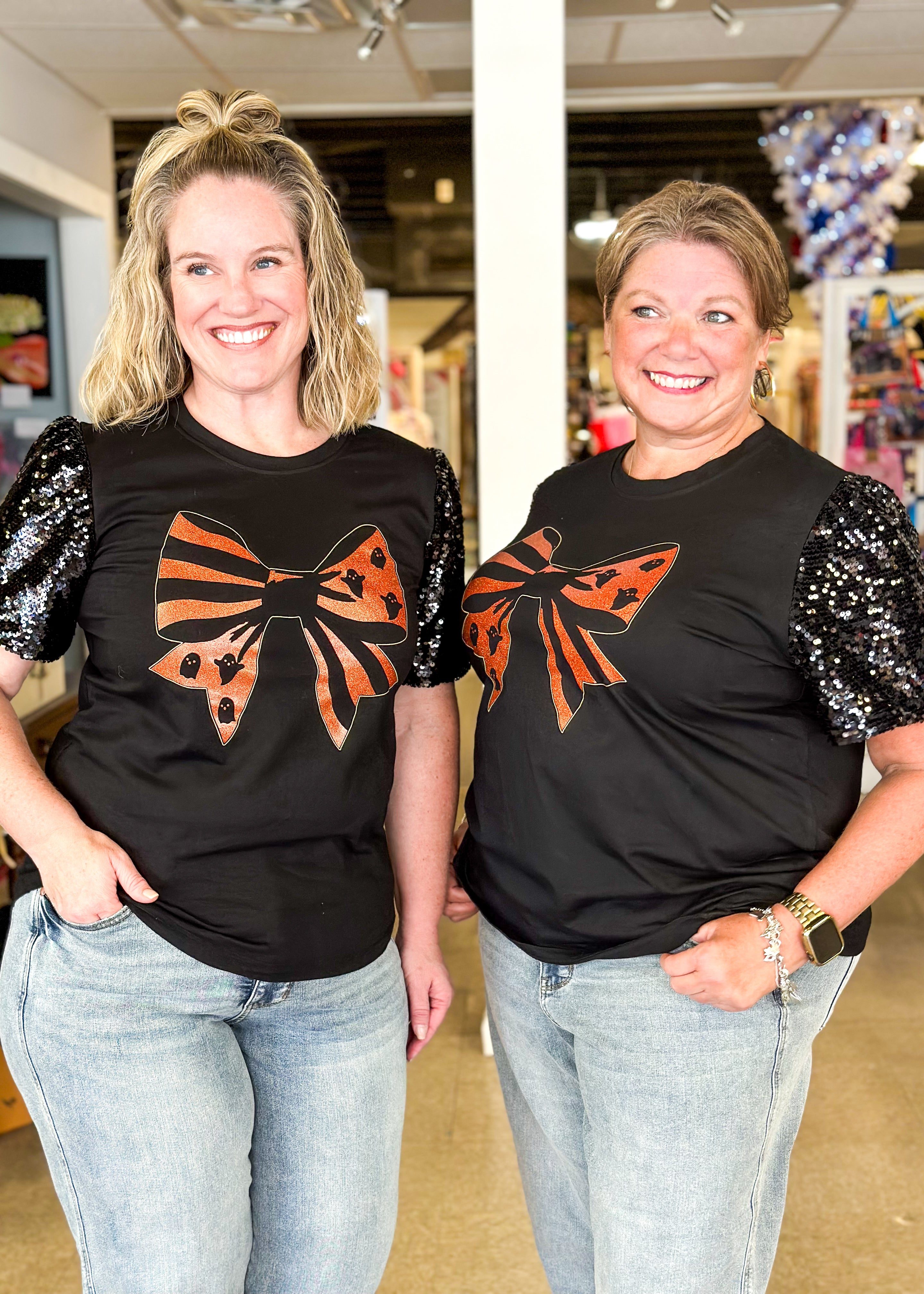 black top with black sequine short sleeves, orange glitter bow with ghosts and stripes