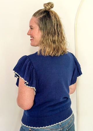 woman in blue ruffle sleeve sweater with white stitched bird