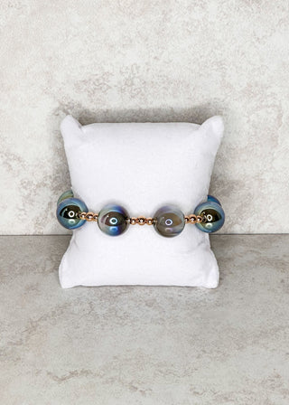 stretch Bracelet with gray and gold accents on a white cushion against a marble background