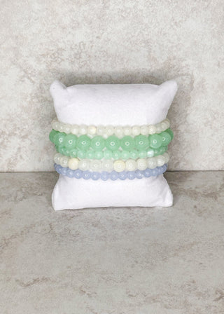 5 beaded bracelets in soft ocean colors displayed on a stand 