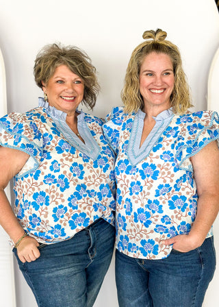 blue floral with large double ruffle short sleeve top - ruffles trimmed in blue and white striped contrast also runs along v neck- ruffle color - brown stems