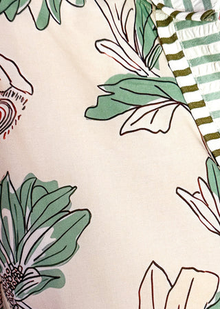 Close up of women's floral dress with sage botanical print, striped seersucker trim, and buttons.