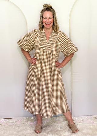 Woman wearing long brown gingham dress with short sleeves