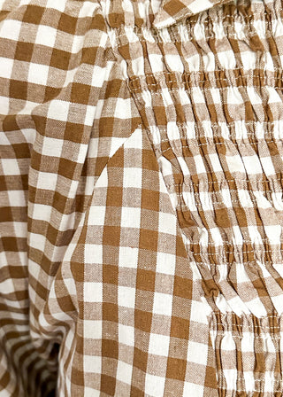 Close-up of a brown and white gingham check blouse with a smocked chest pocket.