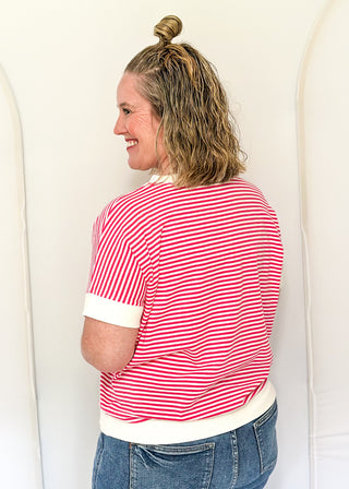 Woman wearing a red and white striped shirt with a white base, standing against a white background.