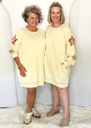 Two women modeling a cream sweatshirt dress with fabric star patches
