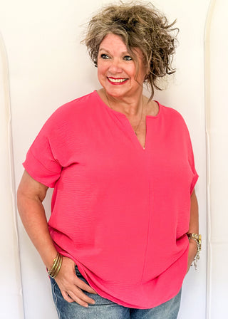 Solid pink textured blouse with a V-notch neckline, short sleeves