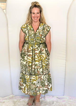 Ruffle cap sleeve maxi dress. off white background with green botanical print.  Dark green piping detail around v-neck, sleeves, bottom tier.  dark green ties on each side of waist. 
