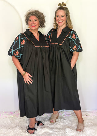Black midi dress with embroidered puff sleeves and a smocked bodice, worn by two models.
