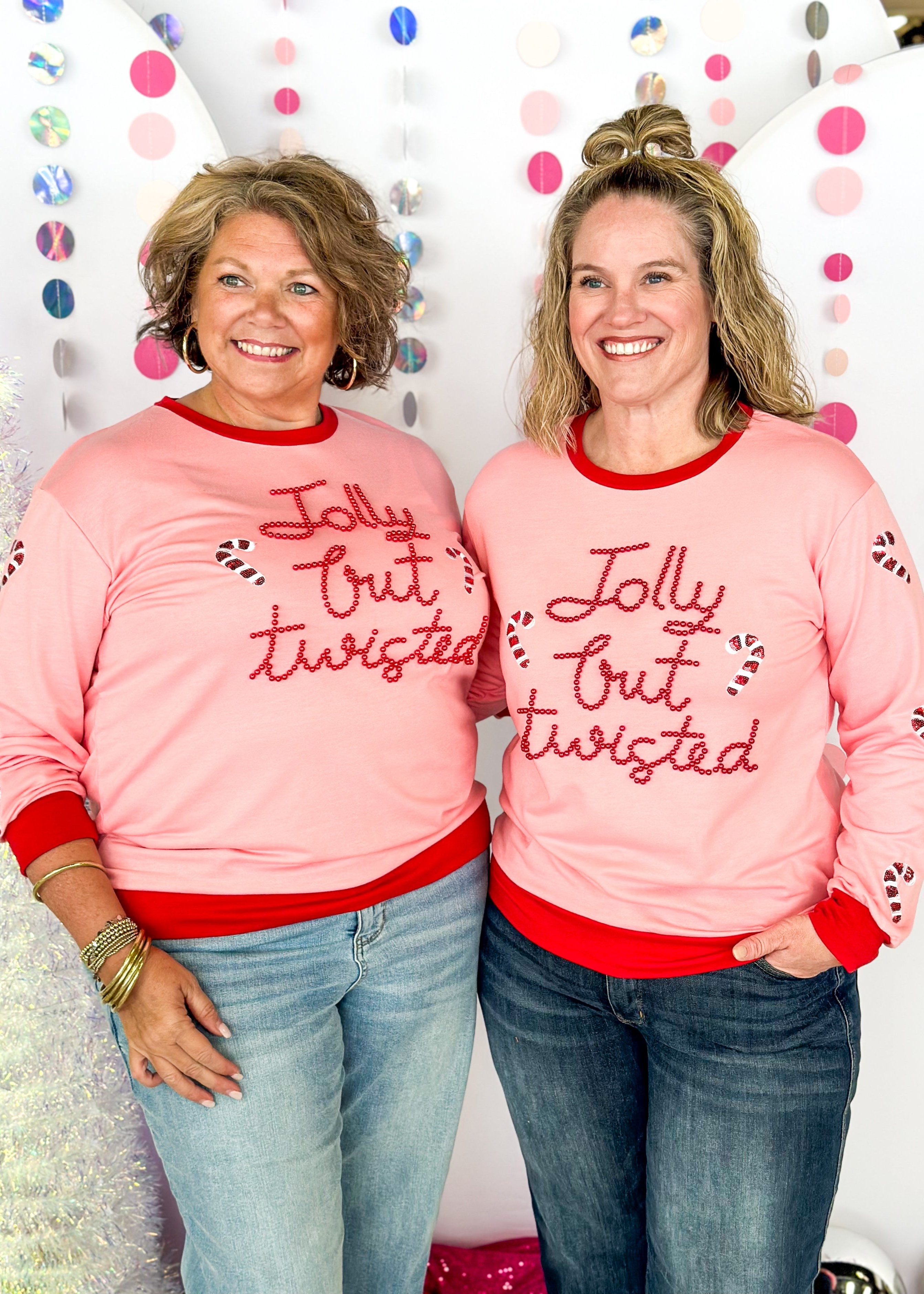 pink long sleeve top with red banding around collar, cuff and bottom - jolly but twisted spelled out in cursive red beads across the front with candy cane sequin patches in front and down the sleeves