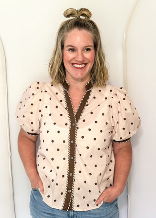 woman wearing Ecru button up top with brown polka dots. 