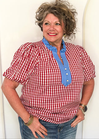 Women’s gingham blouse with decorative buttons and statement neckline detail.