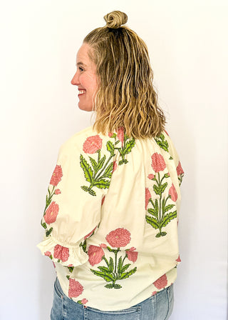 3/4 smocked sleeve cream top with large pink blooms. V-neck with pink trim detail. 