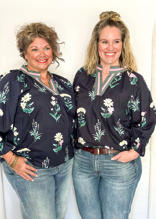 dark navy top with florals in light pink and white with green leaves.  3/4 length sleeve and v-neck with contrast detail in dusty blue and light pink. 