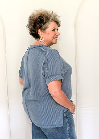 Woman wearing a blue striped shirt and jeans against a white background