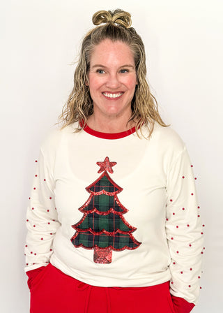 White long sleeve Christmas top with red neckline and cuffs, featuring a plaid Christmas tree appliqué with red sequin trim on the front. Red pearl accent the sleeves for a festive touch.”