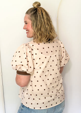 woman wearing Ecru button up top with brown polka dots. 
