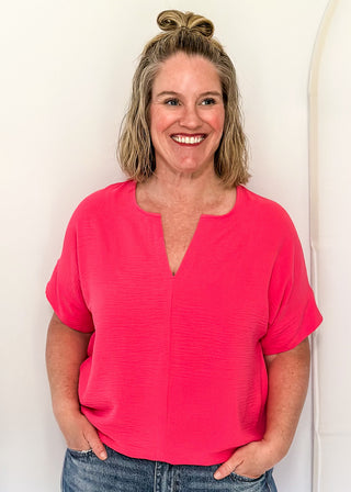 Solid pink textured blouse with a V-notch neckline, short sleeves
