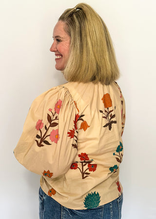 Ecru floral blouse with colorful flowers, contrast turquoise and rose trim, and ruffled neckline
