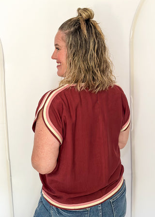 women wearing brick red top with cap sleeves and crew neckline, styled with jeans.