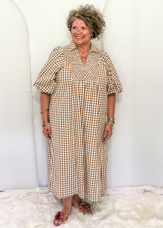 Woman wearing long brown gingham dress with short sleeves