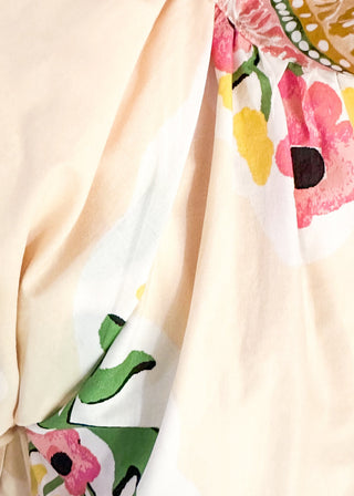 close up of women's short sleeve ecru top with pink floral bundles and decorative hem and collar. 