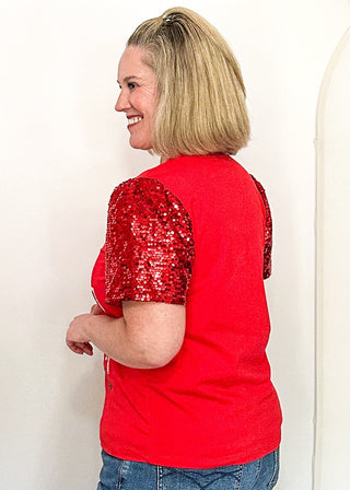 side view of woman modeling a short sleeve red sequin sleeve top with sequin drinks on the front. 