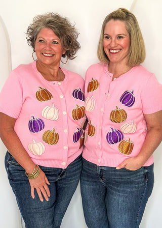 Two women modeling pink shot sleeve sweater with glitter pumpkins in purple and orange 