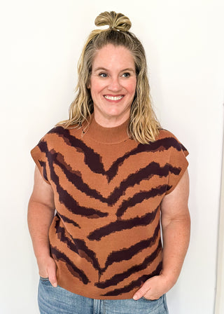 Woman wearing a brown sleeveless top with tiger stripe pattern against a white background