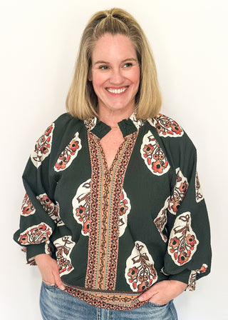 Forest green boho print top featuring smocked collar large floral bundles and colorful border trim.