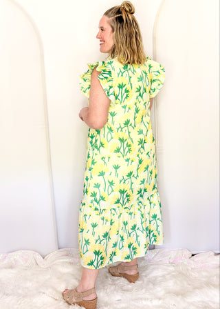 Women’s flowy maxi dress with green and yellow floral pattern and ruffle sleeve detail.