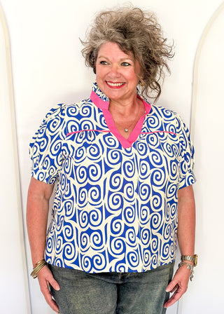Royal blue swirl print top featuring pink contrast trim, puff sleeves, and lightweight relaxed fit.
