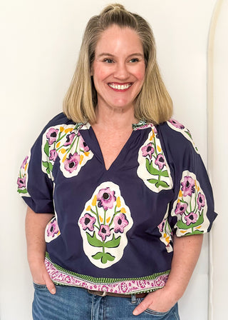 Women’s short sleeve floral blouse in navy with contrast neckline detail, and decorative hem