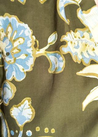 A close-up of a floral fabric print featuring light blue and cream flowers outlined in gold on an olive green background.