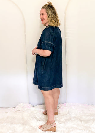 Women's dark blue denim dress featuring statement puff sleeves and contrast stitched detailing around the neckline.