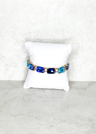 Bracelet with blue gemstones on a white cushion against a light gray background